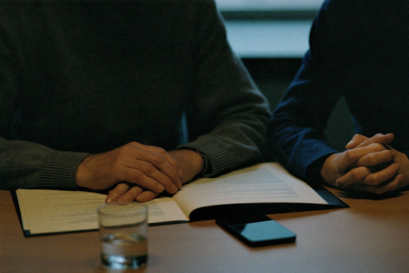 Консультация за столом: документы, стакан воды, телефон экраном вниз